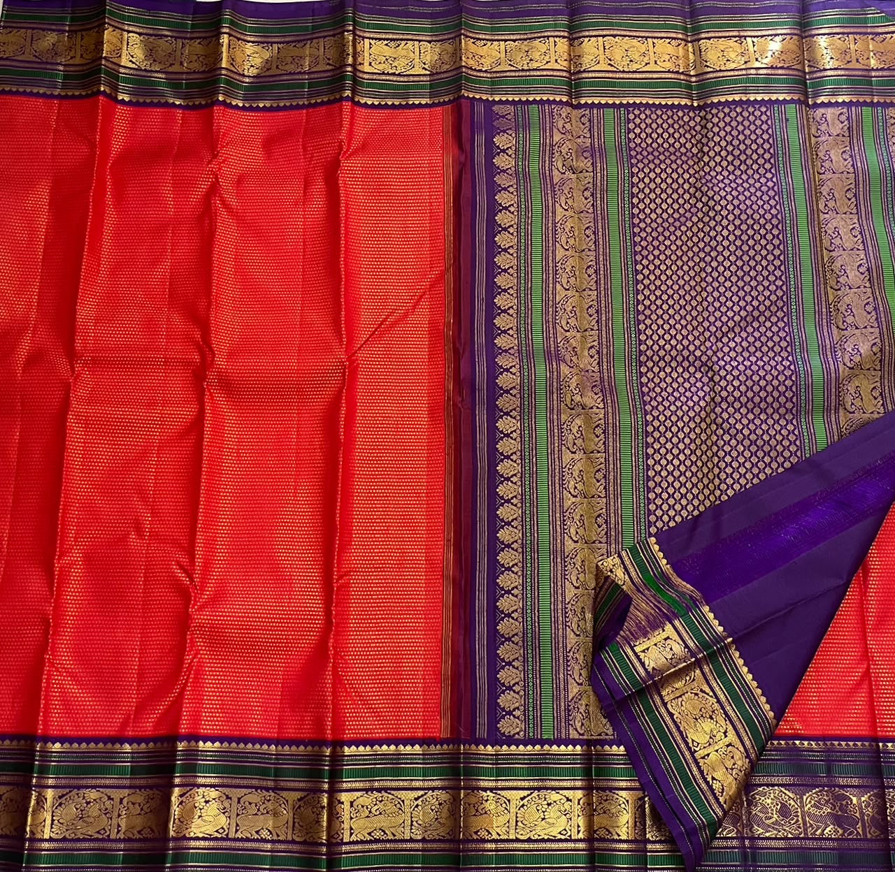 Close-up of deep red silk body with dense all-over repeating gold zari butta shimmer field — Kancheepuram Butta