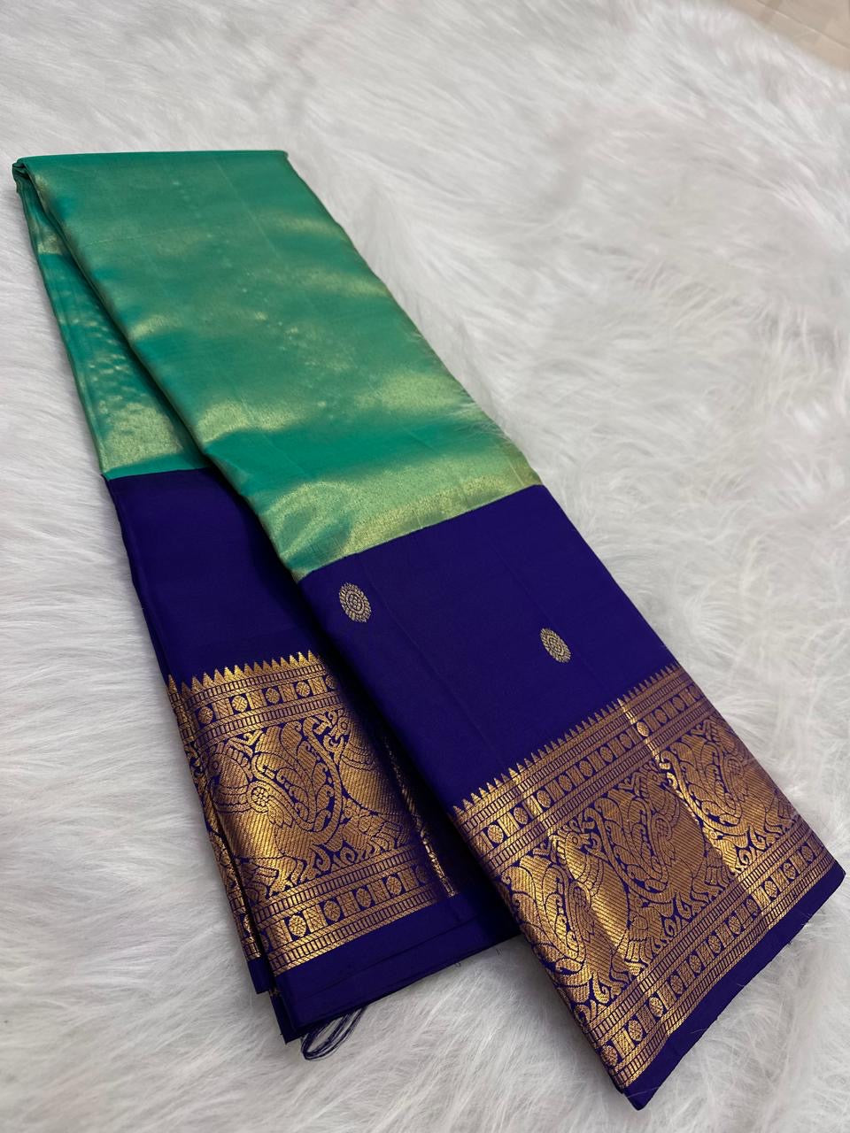 Folded view of the handwoven mint green and royal blue Kancheepuram tissue silk Korvai saree showing body shimmer and gold border