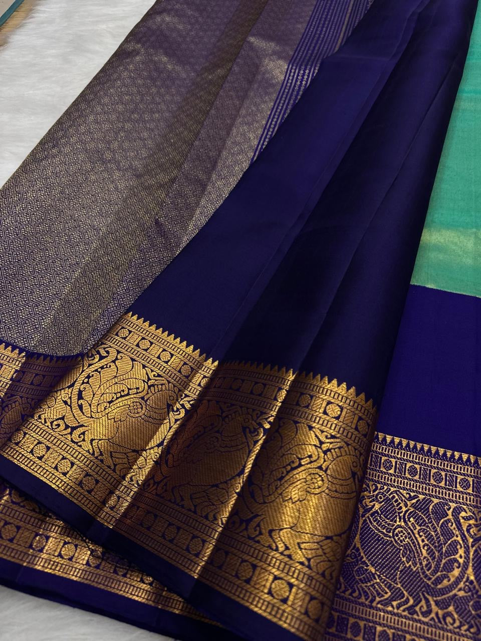 Grand Korvai border of the Kancheepuram tissue silk saree — large paisley and peacock motifs in pure gold zari on royal blue ground