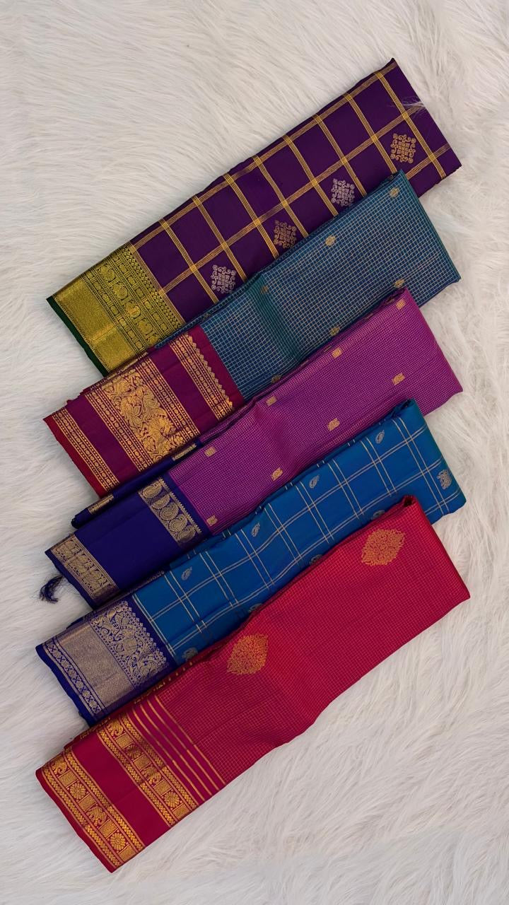 Folded peacock blue and violet pure silk Kancheepuram saree showing shot colour body and violet Yaanai border — handwoven heirloom silk, Silk Mark certified