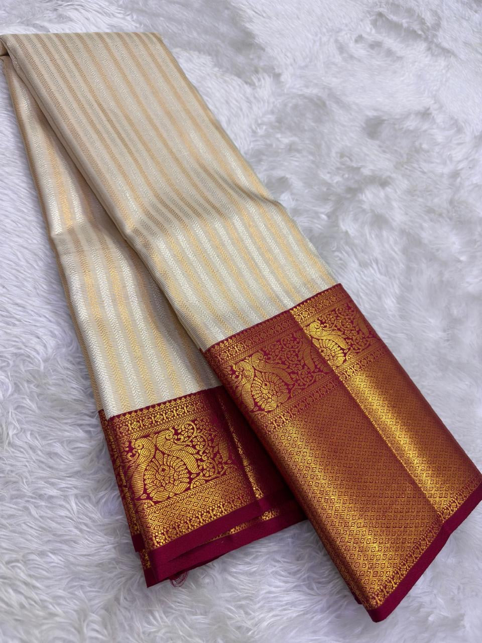 Handwoven Kanchi Pattu Butta saree in ivory with ornate all-over gold zari body and deep crimson Mayil Butta peacock pallu, full folded view