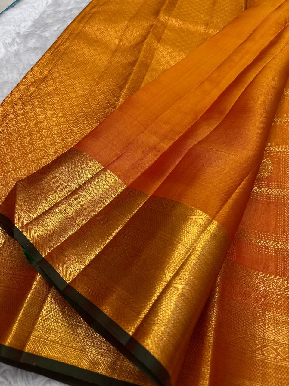 Handwoven Kanchipuram Veldhari saree in shot amber golden orange with green selvedge, Zari Kattam grid, and Maanga Butta, full folded view