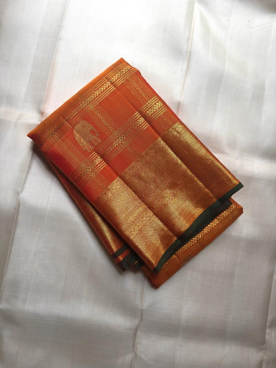 Close-up of shot amber golden orange silk body with Zari Kattam gold grid and green selvedge — Kanchipuram Veldhari