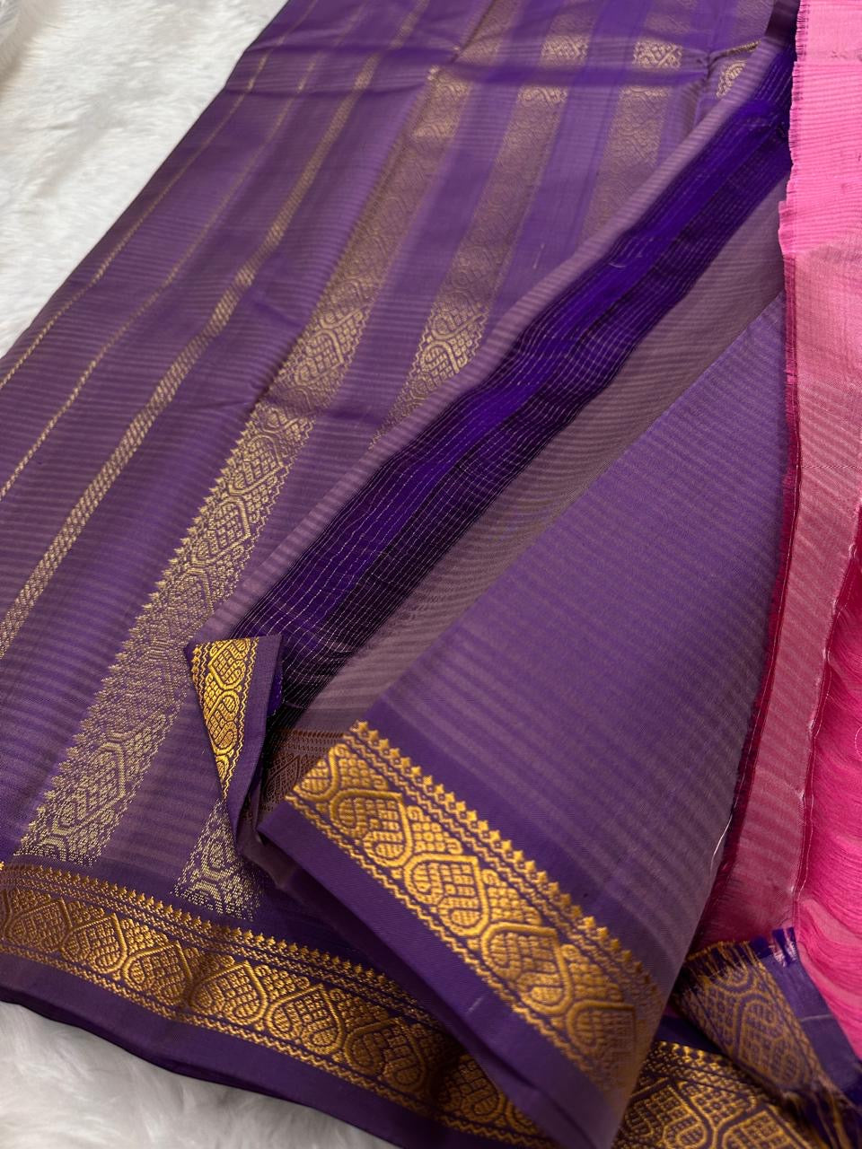 Folded view of the handwoven radiant pink KanchiPattu lightweight silk saree showing Vairaoosi body and purple Varisaipet border