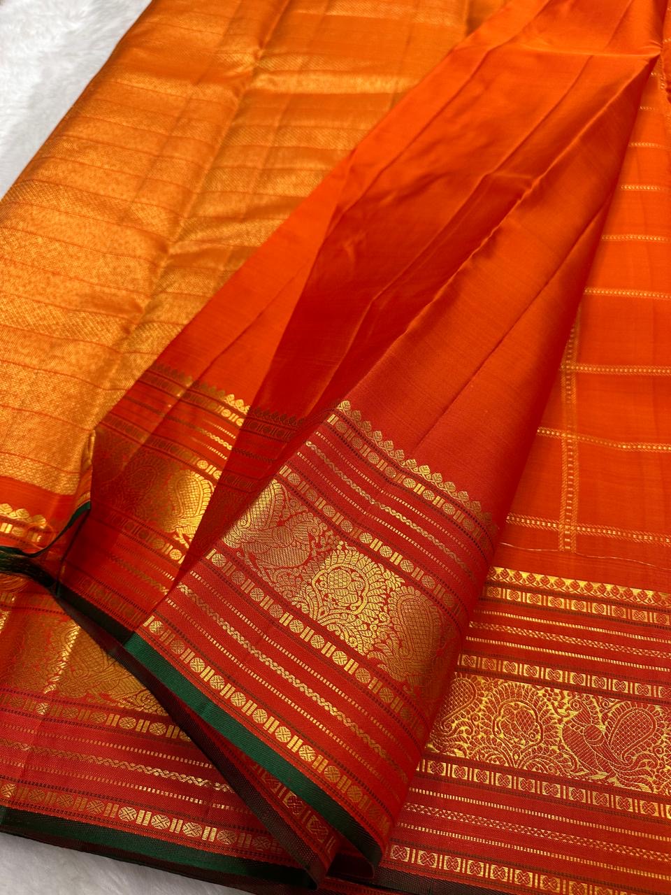 Close-up of burnt orange silk body with fine gold Zari Kattam grid and Kamalam Butta — Kanchipuram saree