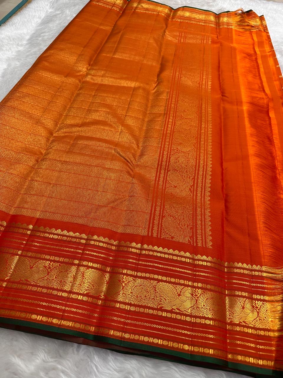 Full folded view of burnt orange Kanchipuram Zari Kattam saree showing body grid and green selvedge border