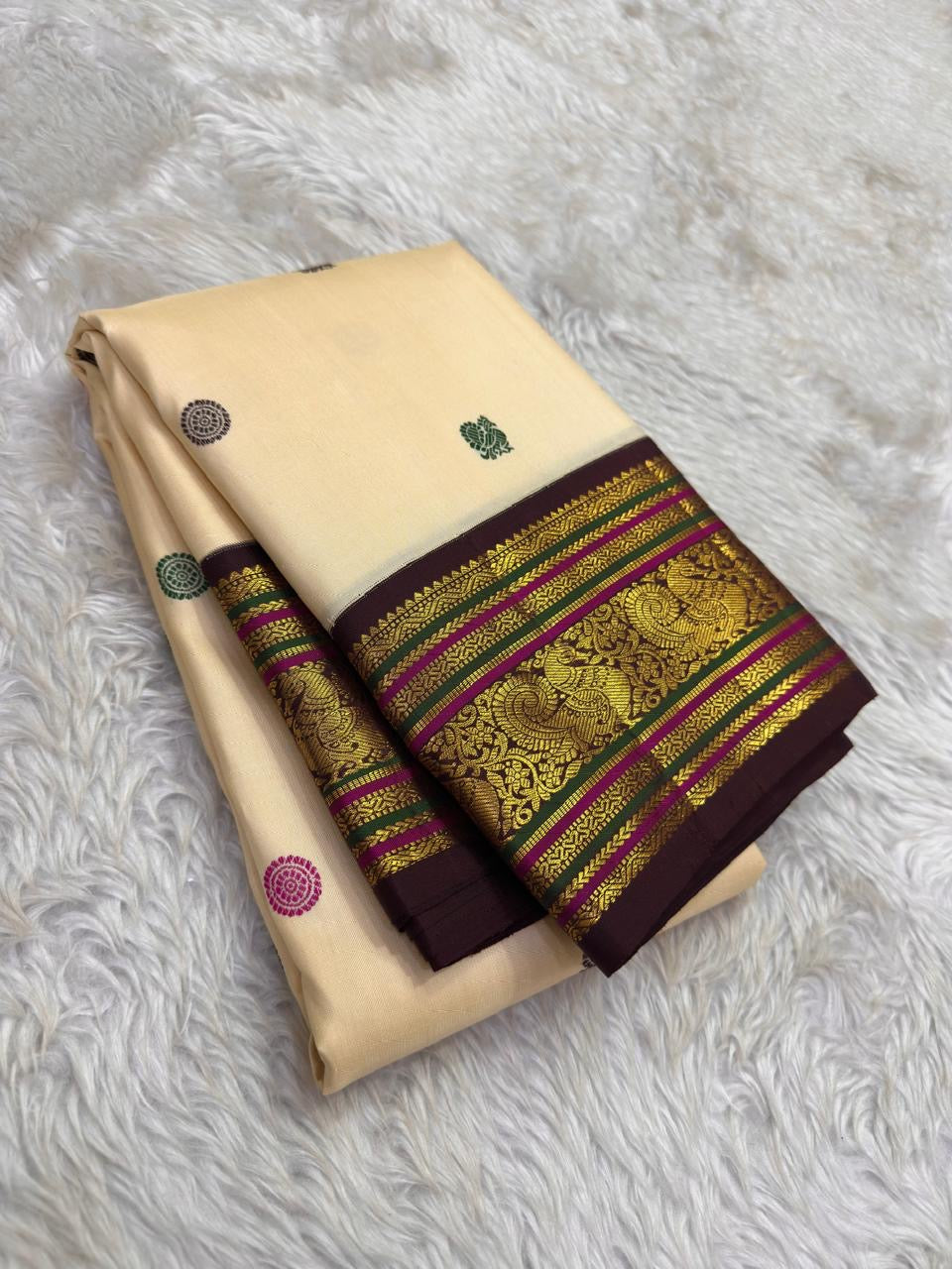 Close view of the ivory silk body showing Yaanai Butta elephant motifs woven in arakku red silk thread across the full length