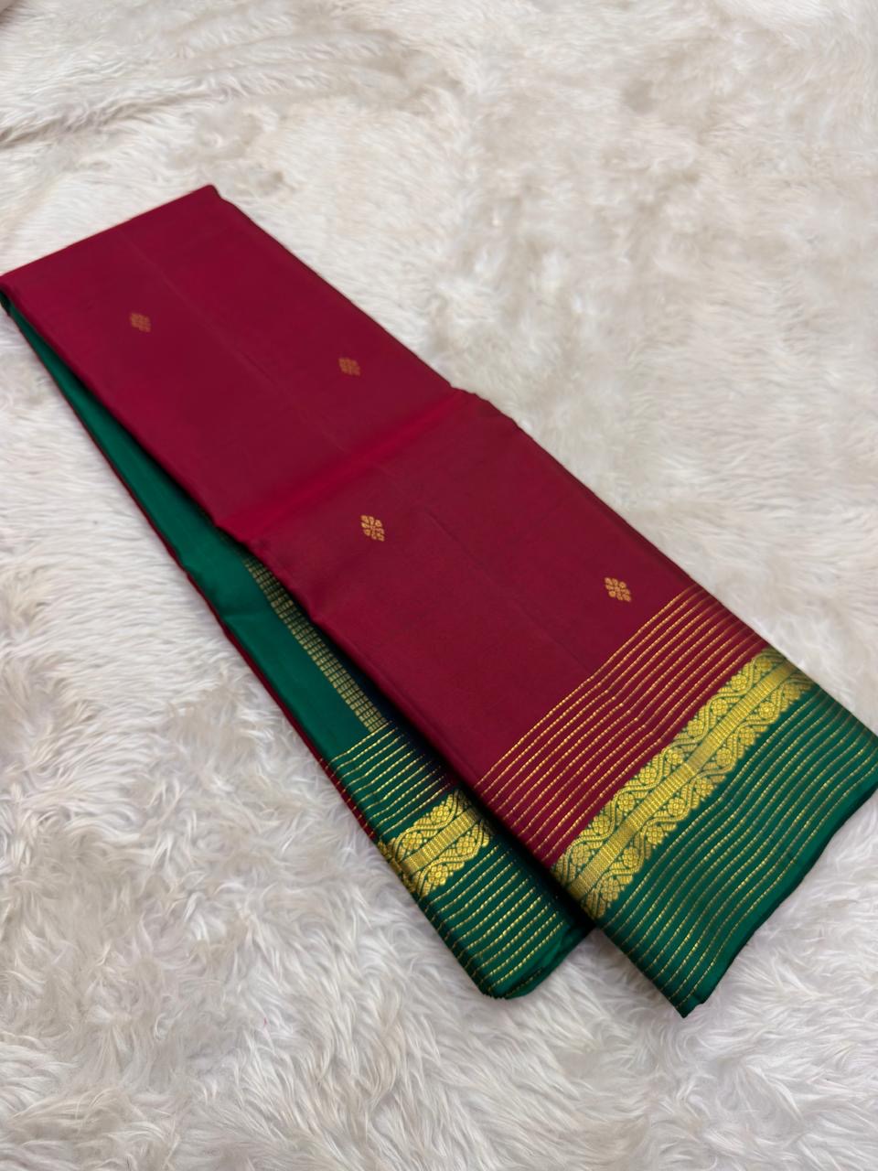 Folded view of the handwoven deep rose and bottle green Kanjivaram lightweight Korvai silk saree showing Kamalam Butta body and multicolour Varisaipet border