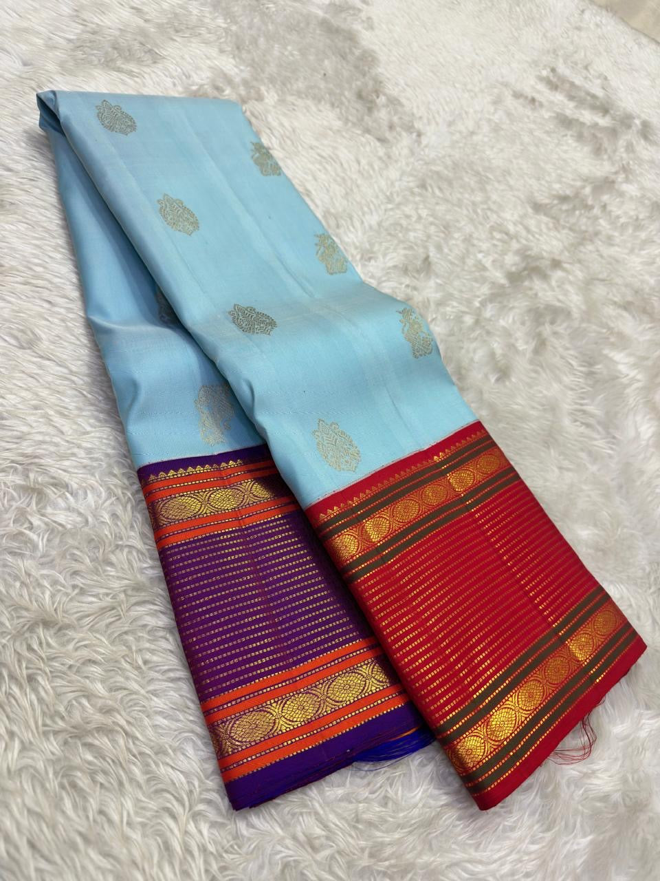 Close view of the sky blue silk body showing Maanga Butta mango motifs scattered in gold zari across the full length