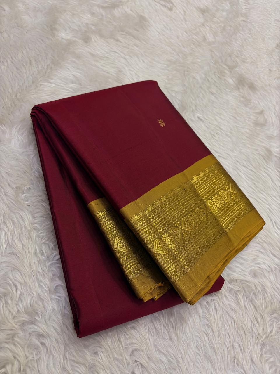 Folded view of the handwoven arakku red Kanjipuram lightweight saree showing Nakshatra Butta body and antique gold Varisaipet border