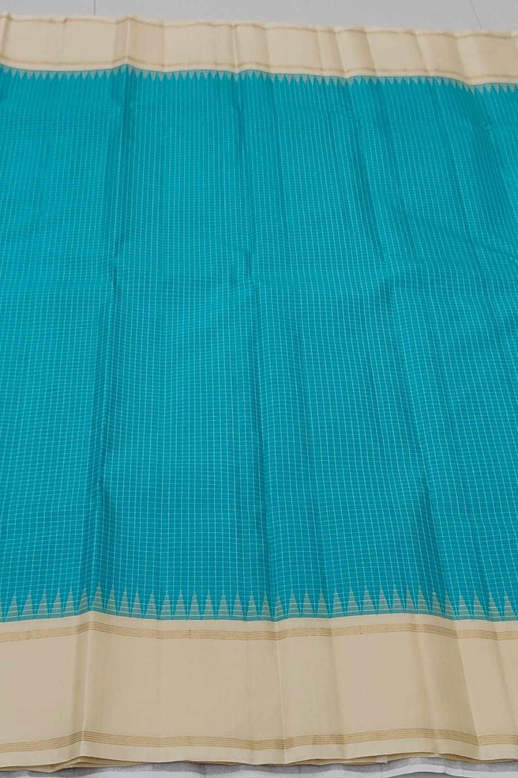 Border detail showing the Pillayar Reku in pale gold zari at the peacock blue to ivory transition on the Kanjipuram saree
