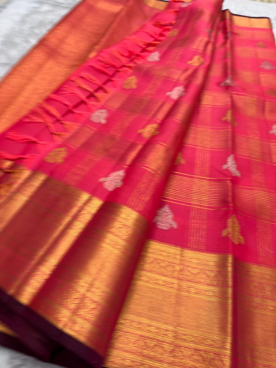 Handwoven KanchiPattu Veldhari saree in shot coral-magenta with Zari Kattam grid, Maanga Butta, and deep maroon antique gold pallu, full folded view