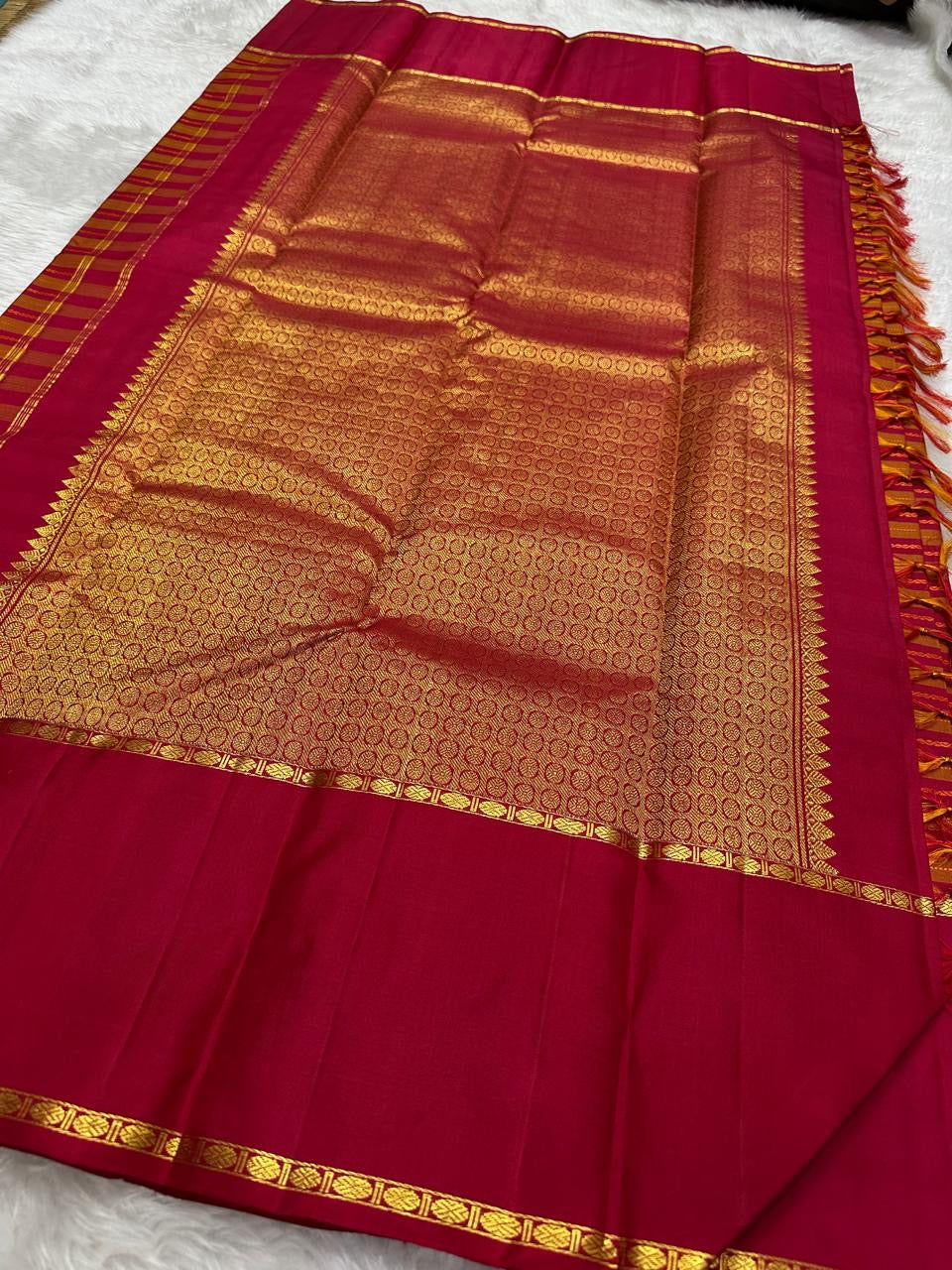 Folded view of orange and arakku red handwoven pure silk Kanjipuram saree with Vazhaipu Veldhari stripe body and Korvai border