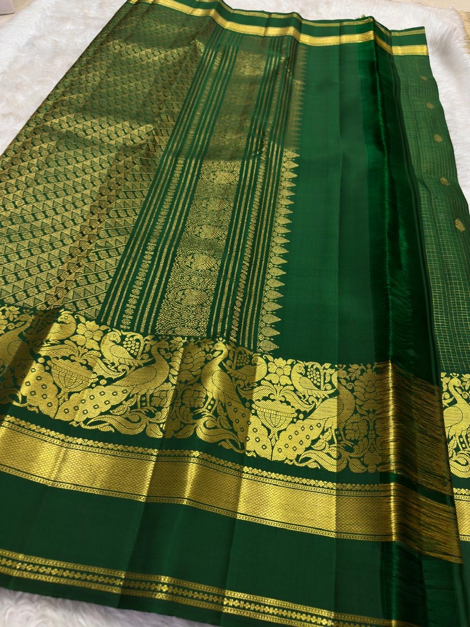 Full folded view of forest green Kanjivaram Zari Kattam saree showing grid body and grand peacock pallu