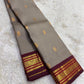 Close view of the steel grey silk body showing fine woven stripe structure and scattered Pavun Butta in gold zari
