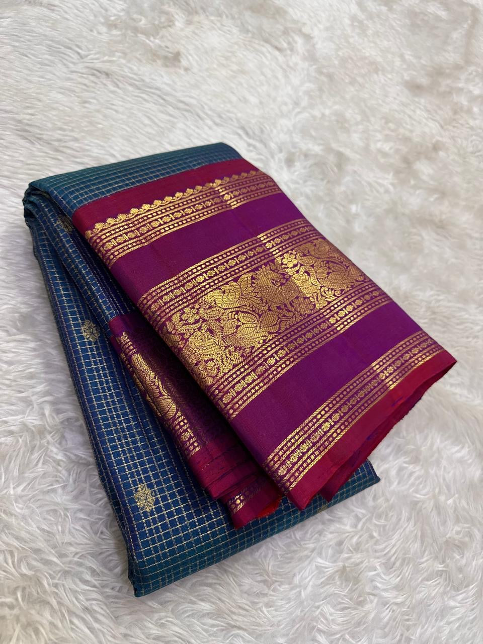 Close-up of deep teal Zari Kattam silk body showing fine intersecting gold zari grid and scattered gold buttas on pure silk Kanjivaram saree