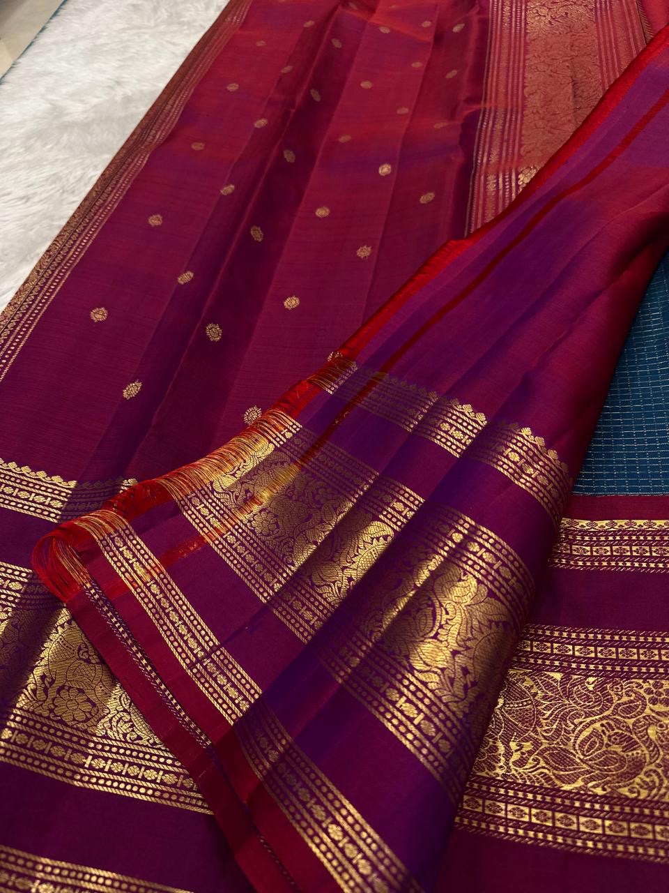 Folded view of teal and arakku red handwoven pure silk Kanjivaram saree with Zari Kattam body and Rettapet elephant border
