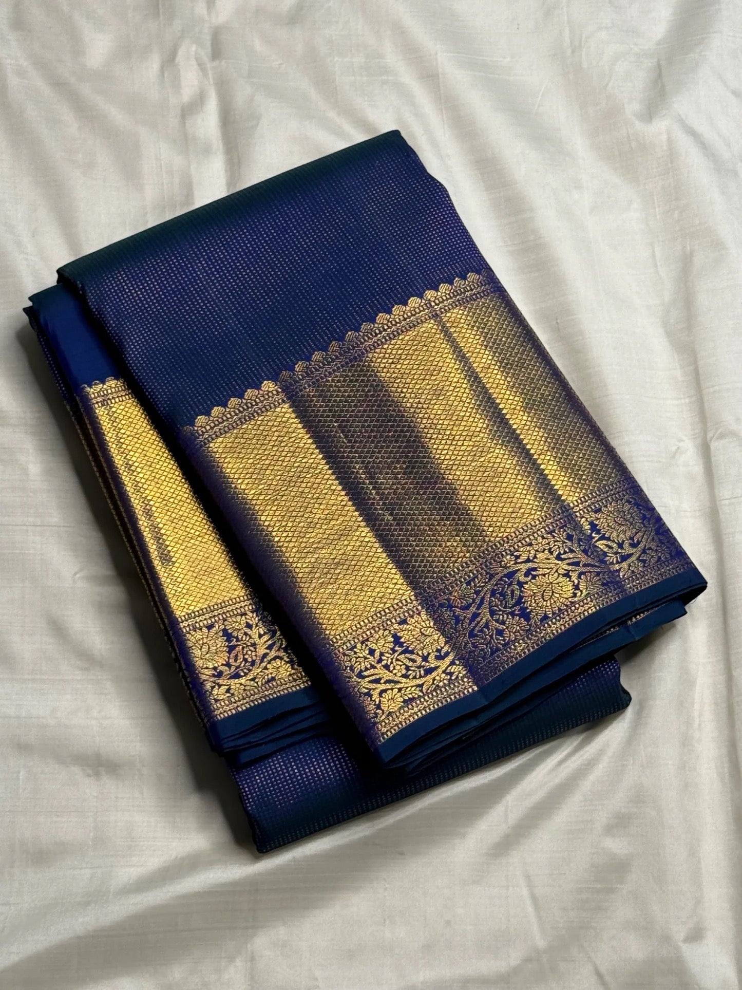 Navy blue Kanchipuram saree body with peacock blue-green shot colour and luminous zari grid — close-up