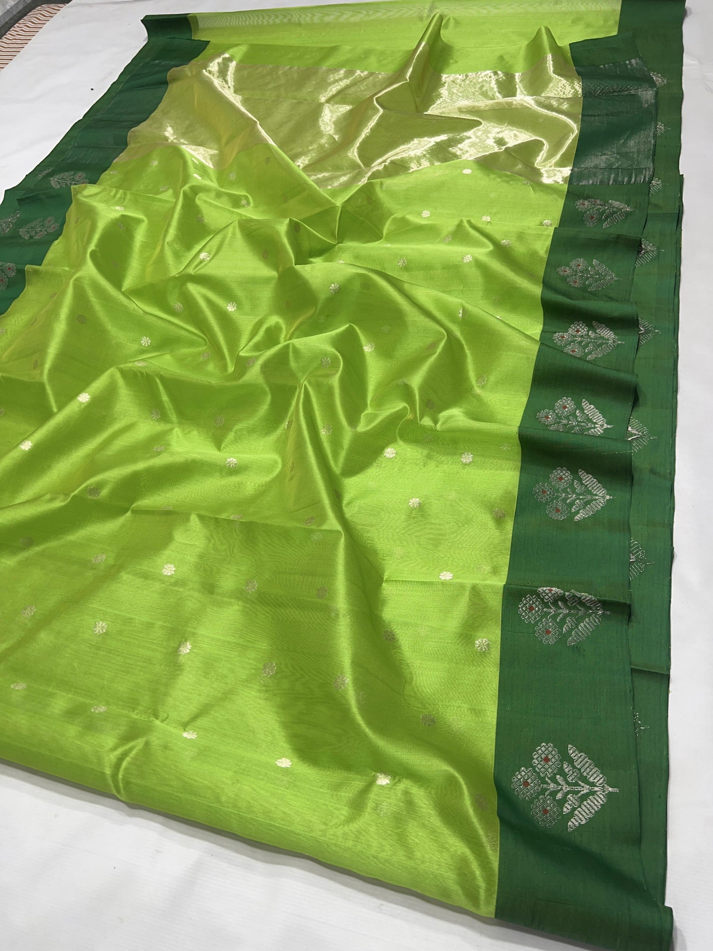 Full view of the Parrot Green handloom Pattu Silk Chanderi saree with silver buttas and forest green border