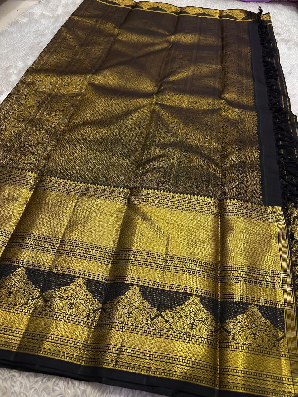 Pure Kanchipuram silk saree pallu spread showing gold zari panels, diamond pattern field, and black tassels, available in the USA