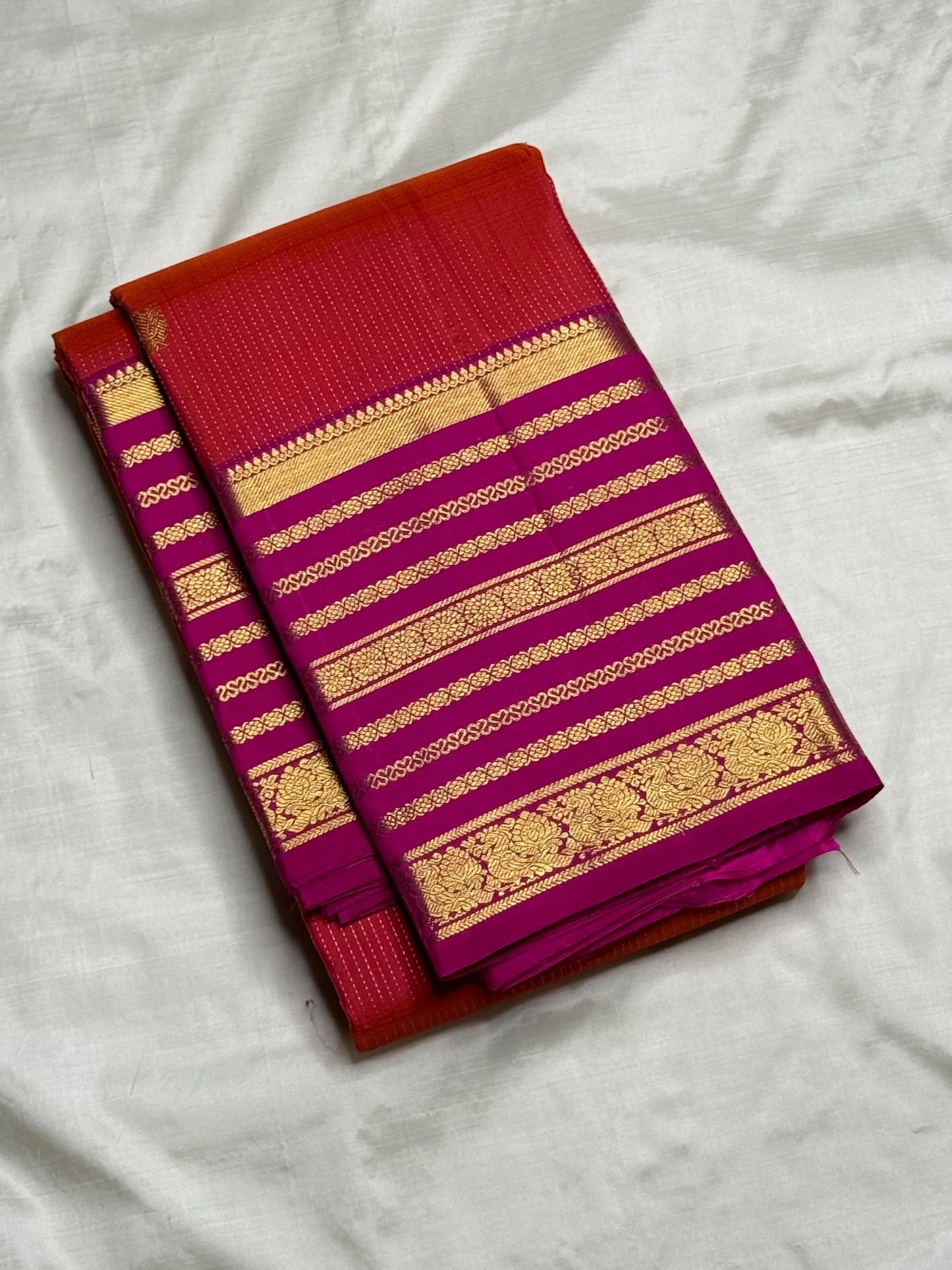Deep orange-red Kanchipuram saree body with continuous Vairaoosi zari lines and Kamalam butta — close-up