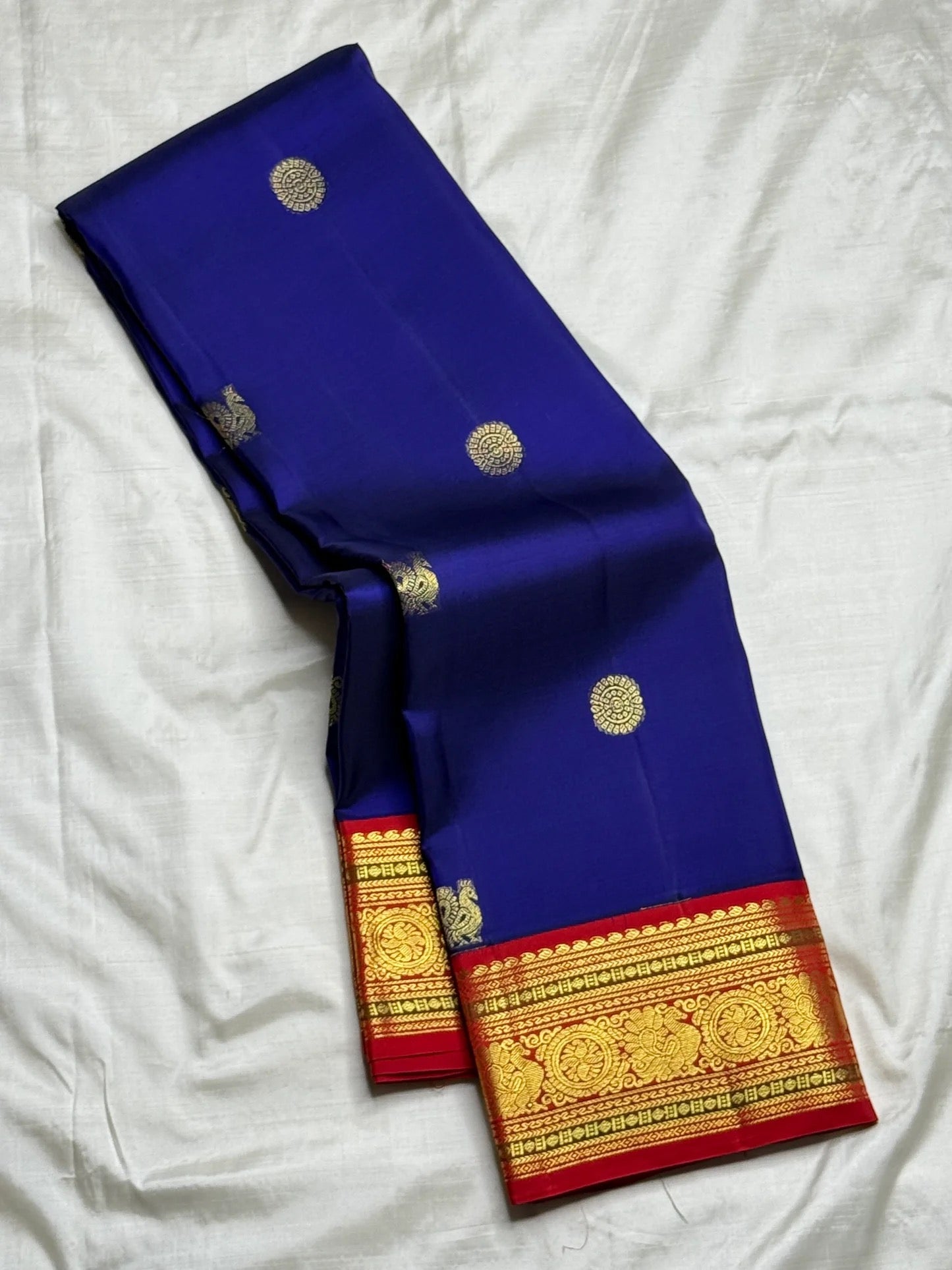 Royal blue and red Kanchipuram butta saree folded flat — full length view