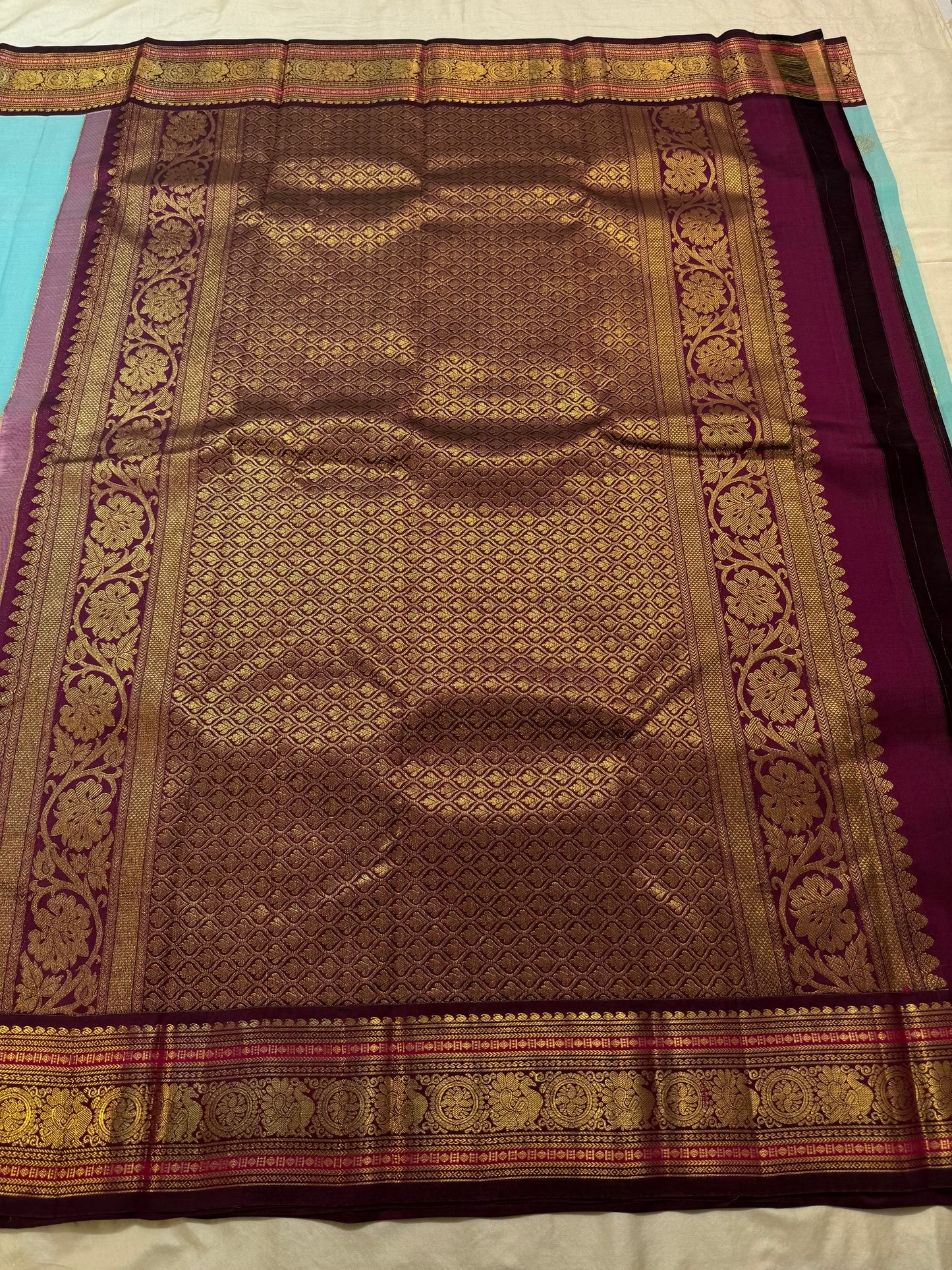 Pale sky blue Kanchipuram saree body with scattered Kamalam and Kili butta in gold zari — close-up