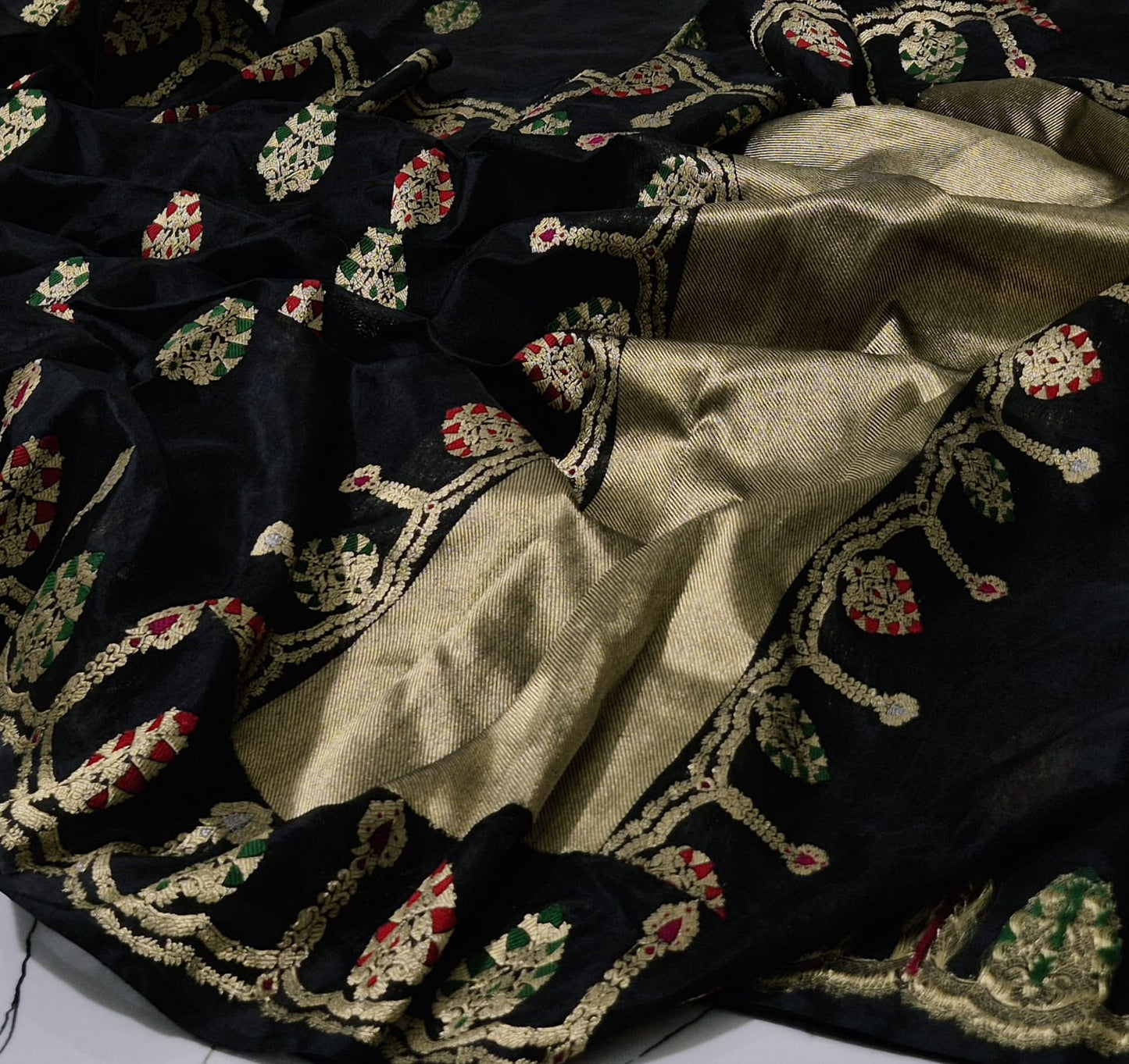 Black Pattu Silk Chanderi saree showing gold woven motifs, green red accents and metallic pallu