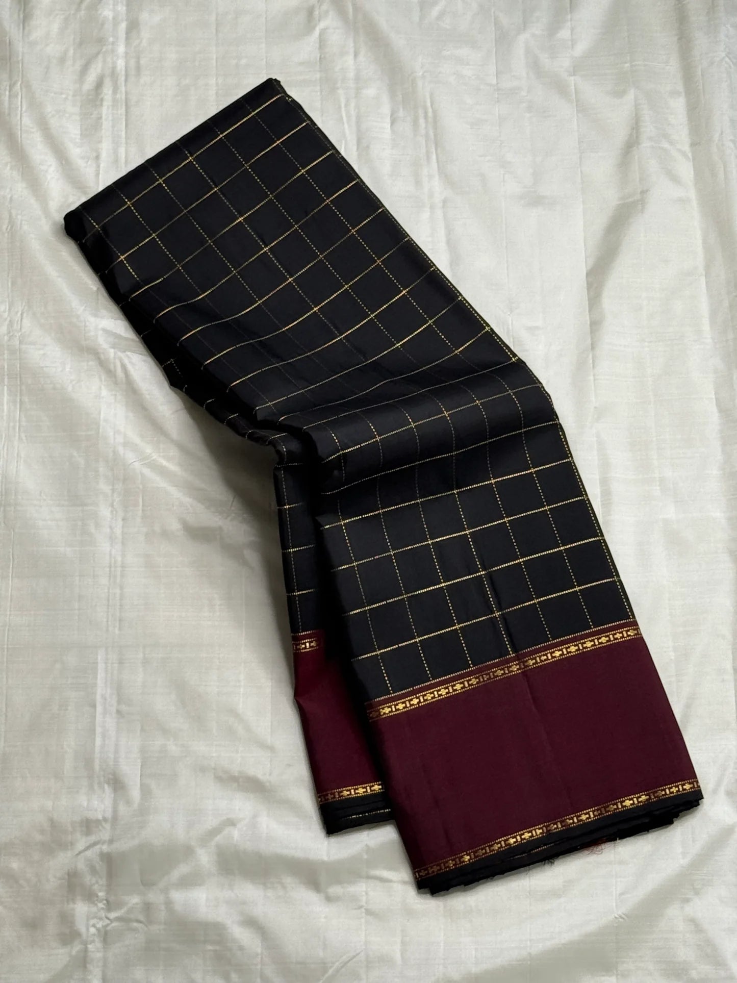 Angled drape of Pure Kanchipuram Silk Saree showing black checked body and maroon zari border detail