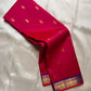 Rani pink Pure Kanchipuram silk saree shown draped with scattered gold zari buttas and blue zari woven border.