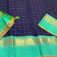 Closeup of sea green Pure Kanchipuram silk saree border with gold zari woven bands and tassels beside navy checked body