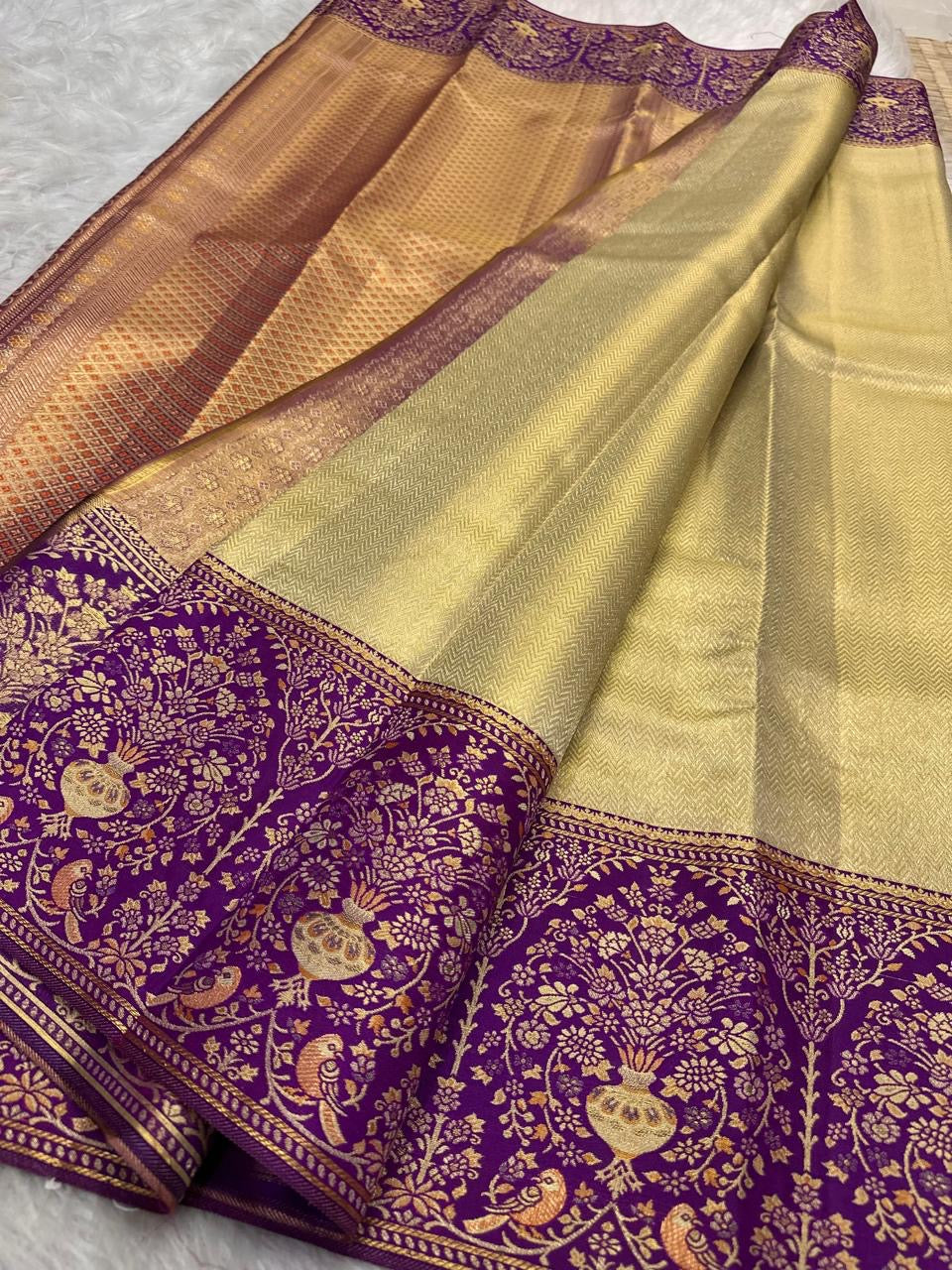 Kanchana Purple border densely woven with gold floral jaal and stylized birds on Antique Gold Kanchipuram silk.