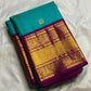 Folded Turquoise Blue Kanchipuram Korvai saree showing Deep Purple border with broad antique-gold zari and figurative motifs.