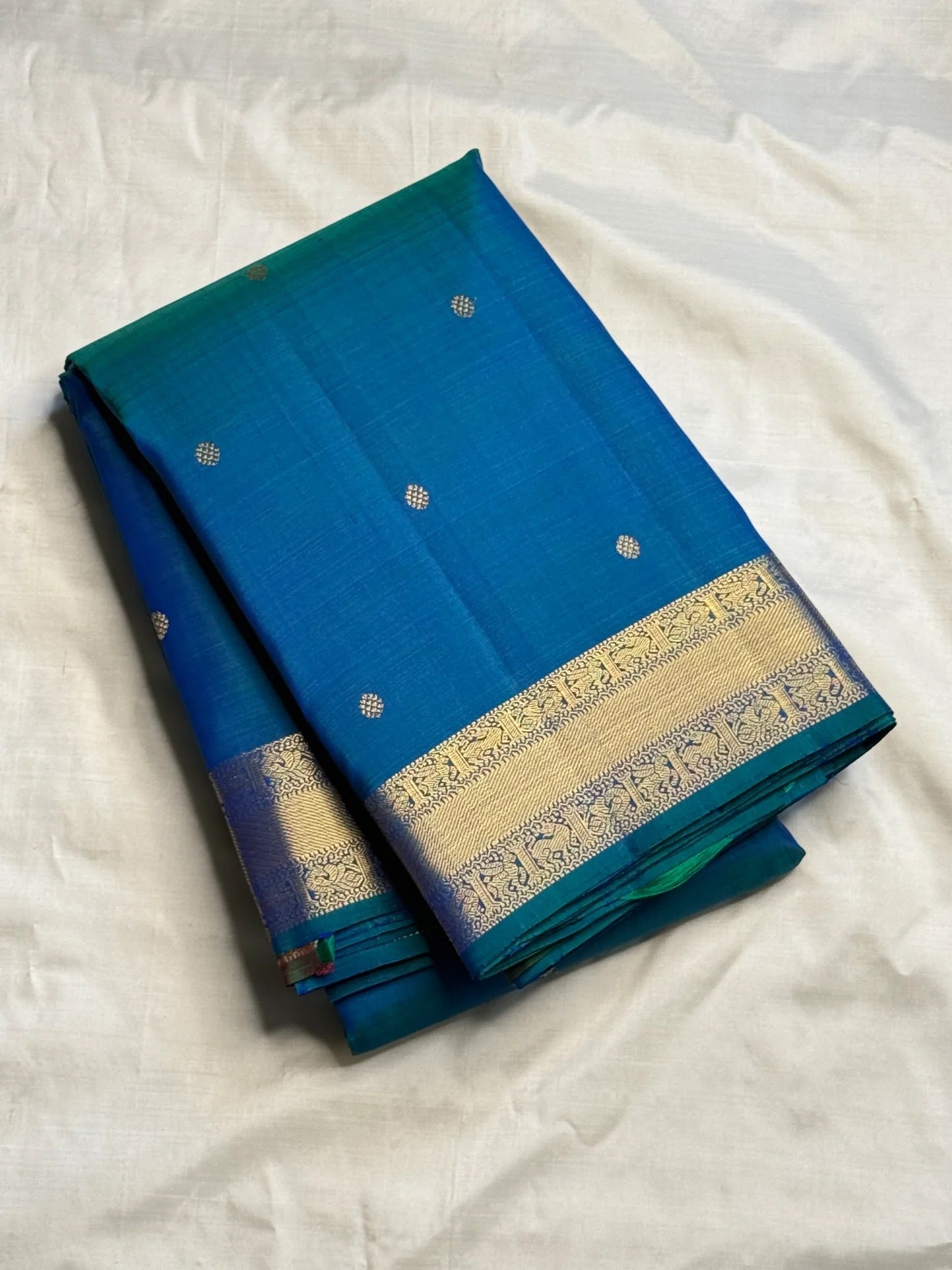 Teal zari border detail on a peacock blue KanchiPattu Butta saree