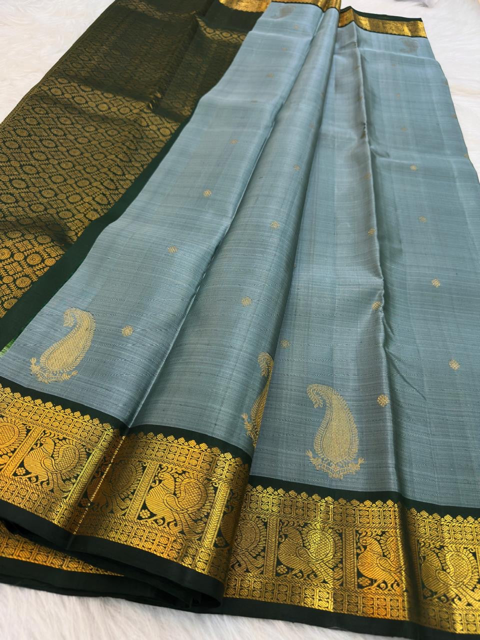 Close view of repeating Mayil motifs, geometric lattice and gold zari on deep green border