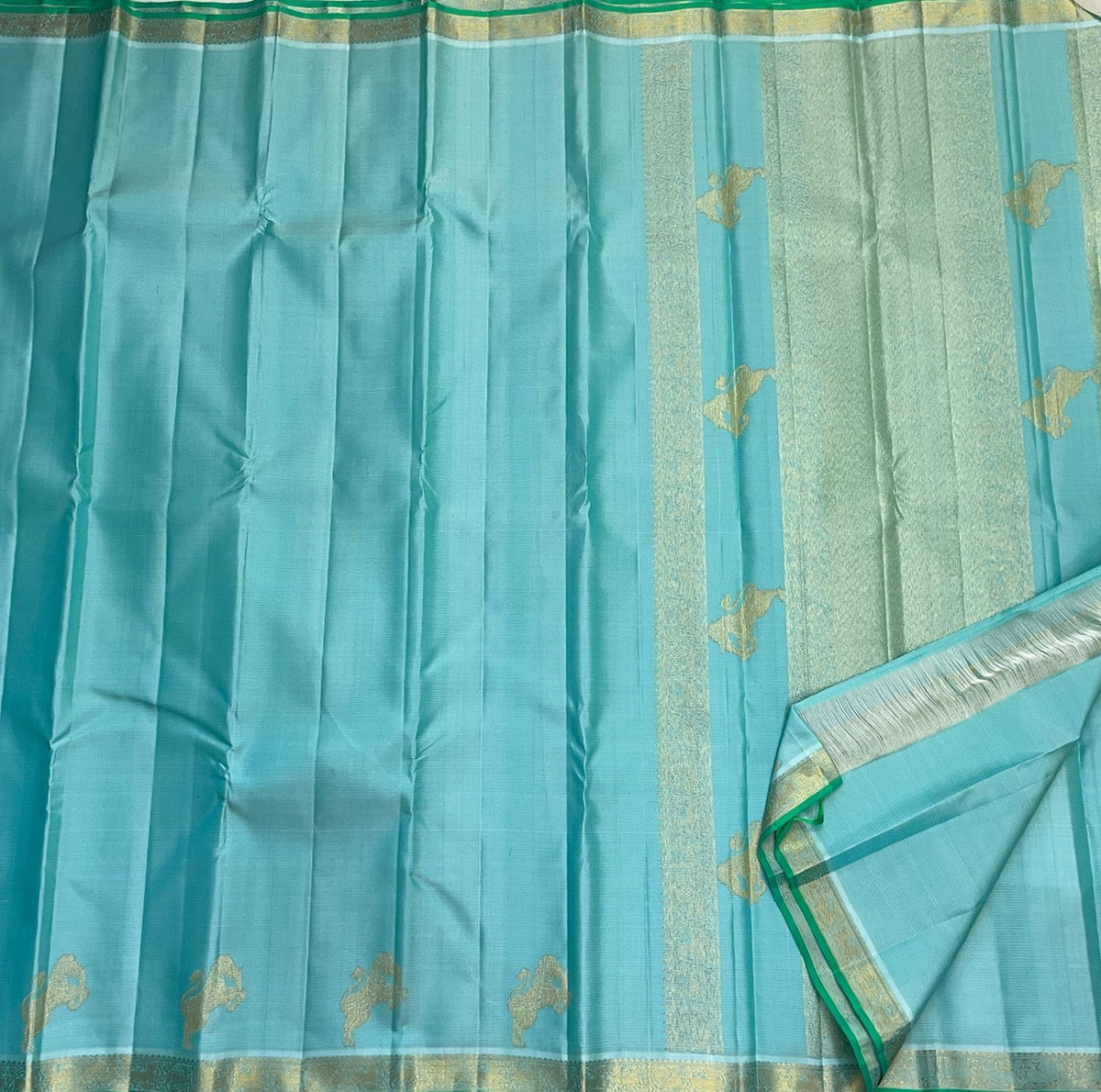 Close view of soft gold zari motifs woven across pale aqua Kanjivaram silk.