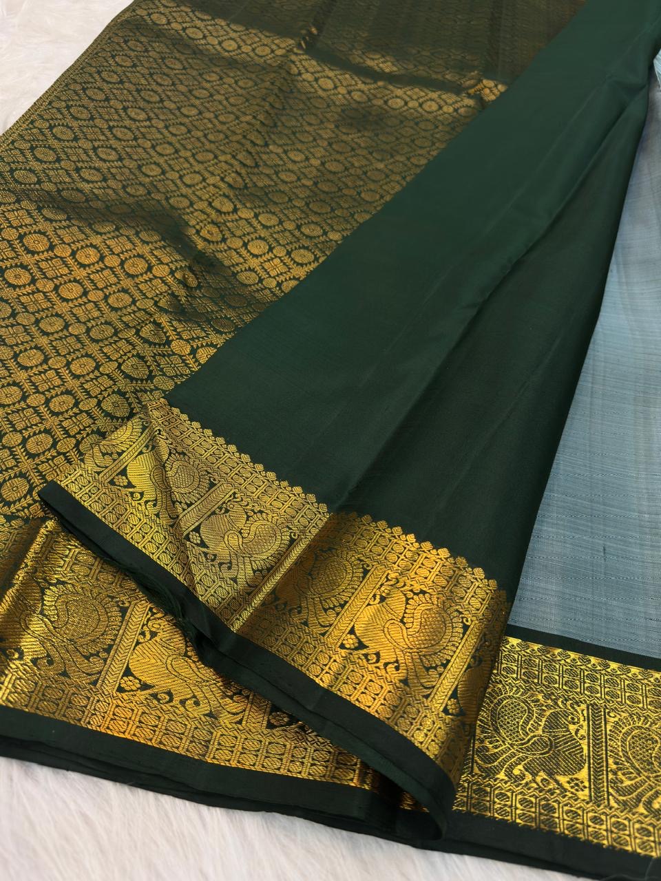 Close view of handwoven warm-gold zari paisley buttas across muted blue pure silk