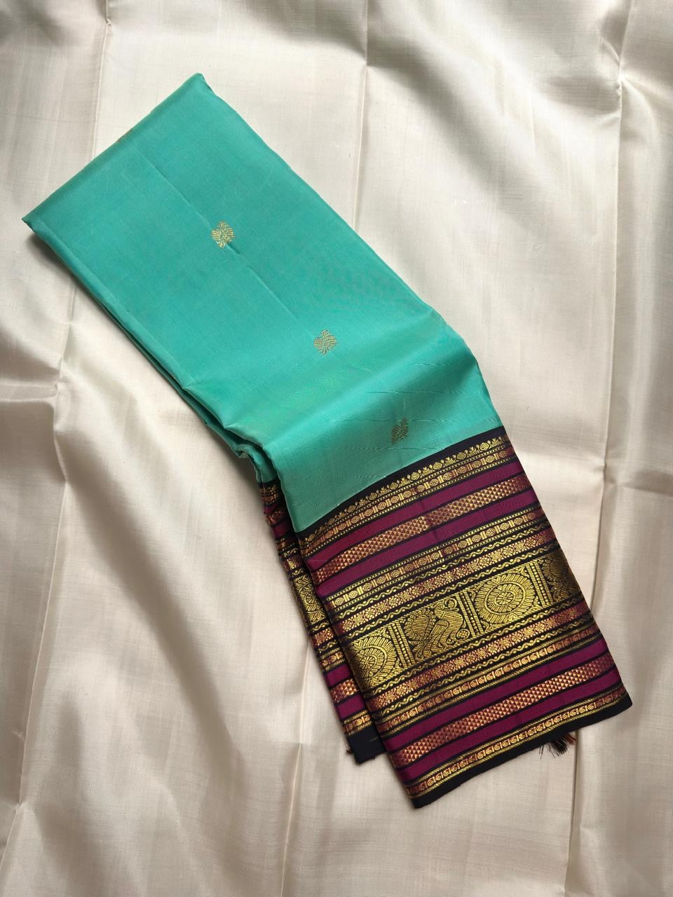 Aqua Turquoise pure silk saree with traditional gold zari peacock buttas and contrast border.