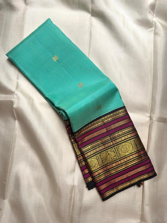 Aqua Turquoise pure silk saree with traditional gold zari peacock buttas and contrast border.