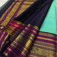 Folded turquoise Kanjipuram saree showing elaborate navy Vadamalli and gold peacock border.