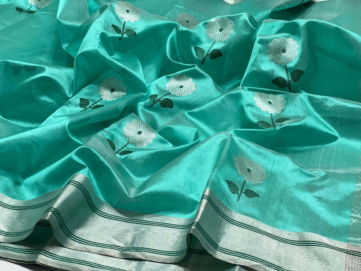 Aqua Turquoise Pattu Silk Chanderi saree with silver floral buttas, deep green leaves and broad silver striped border