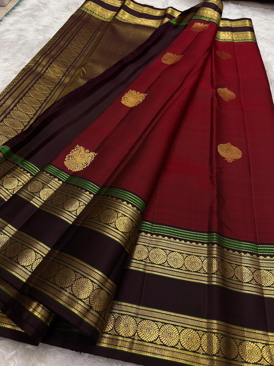 Dense gold zari pallu on the arakku red Kanjivaram rettapet saree.