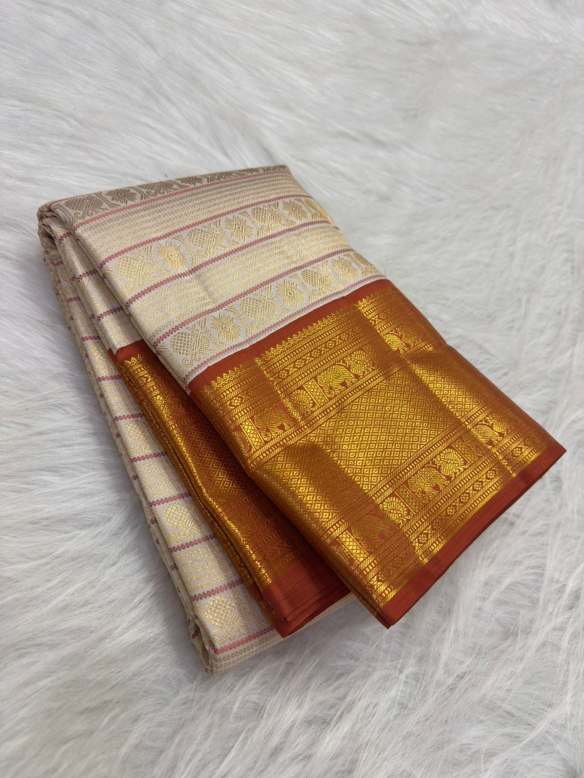 Burnt terra-cotta border with peacocks and Pavun coin motifs, warm-ivory Kanjipuram saree