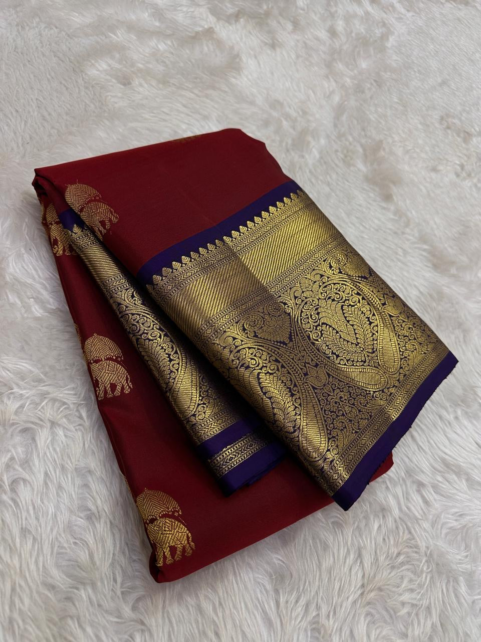 Folded maroon pure silk saree showing gold elephant motifs and oversized paisley border