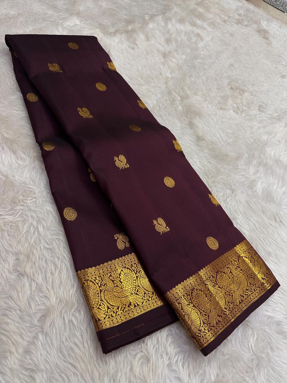 Handwoven Kanjeevaram silk saree featuring traditional gold buttas across a deep cocoa brown body