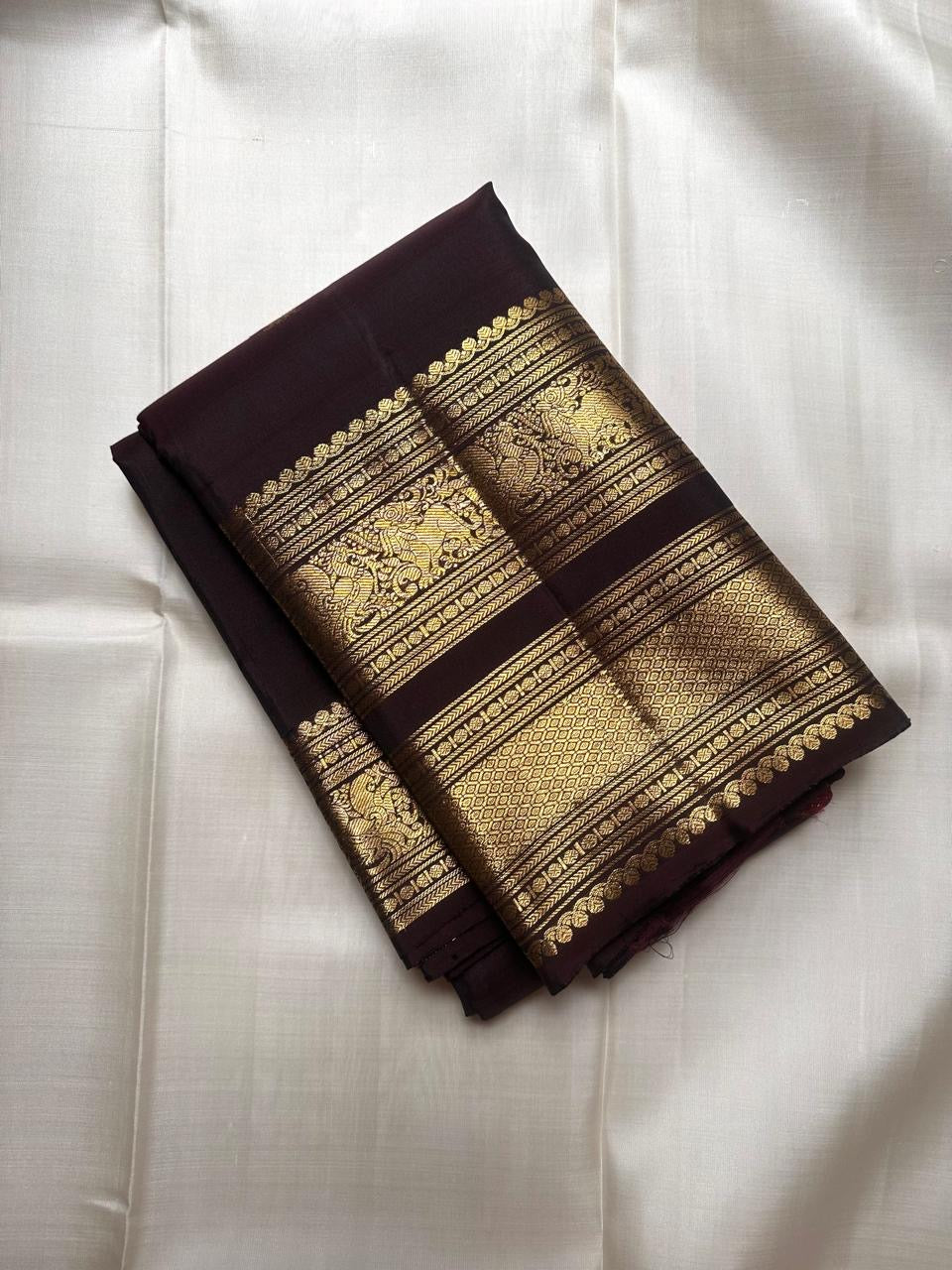 Close-up of gold zari buttas on Aubergine Kanjivaram silk saree body