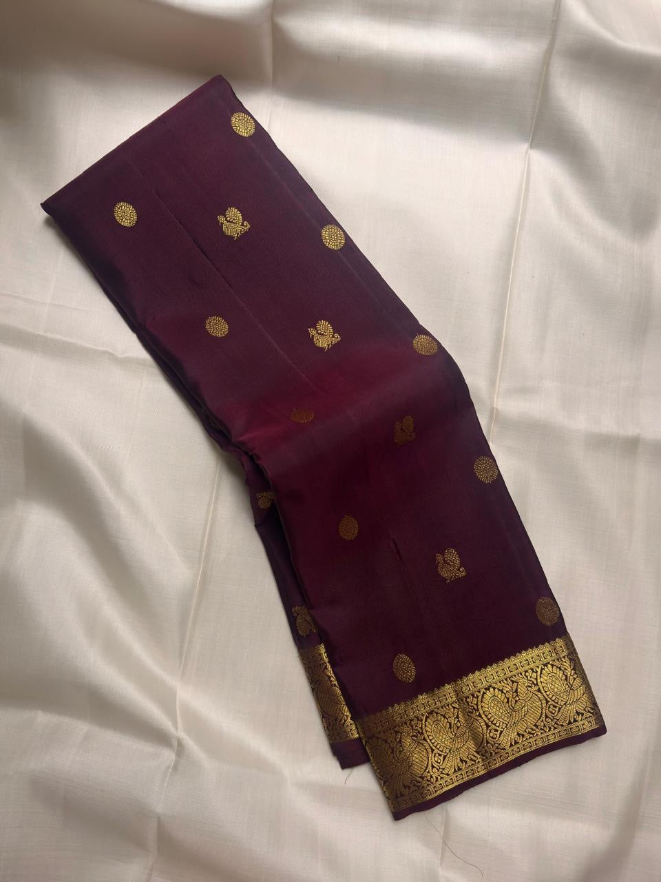 Deep aubergine Kanjivaram saree showing ornate antique gold zari Mayil motif border