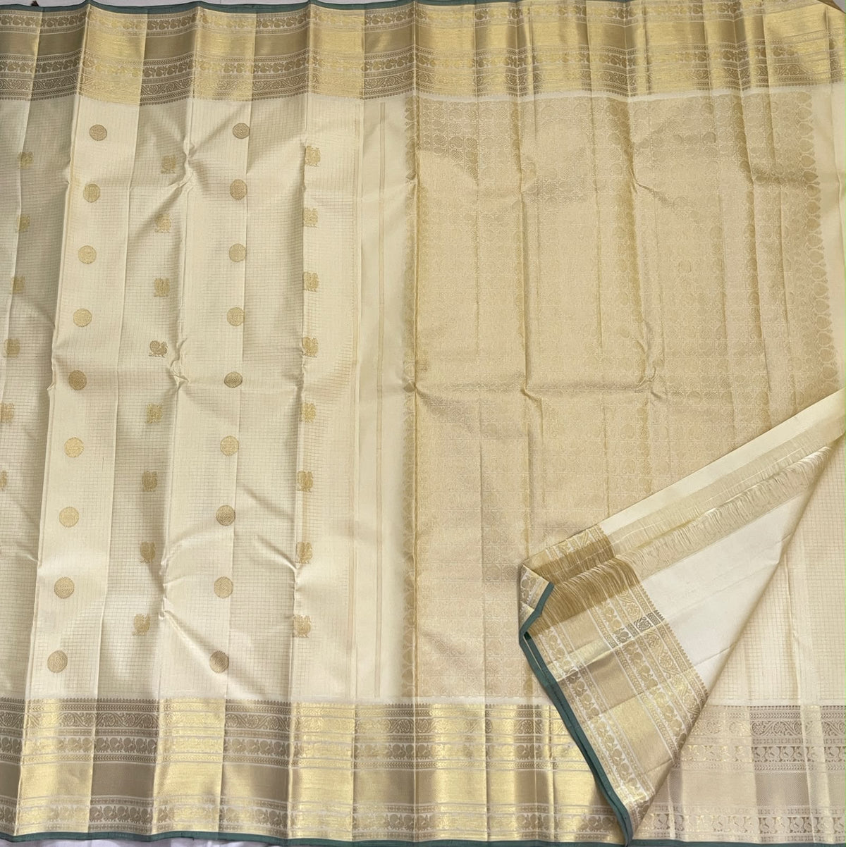Close view of gold zari medallions and Kili buttas on a warm ivory pure silk Kanchipuram saree