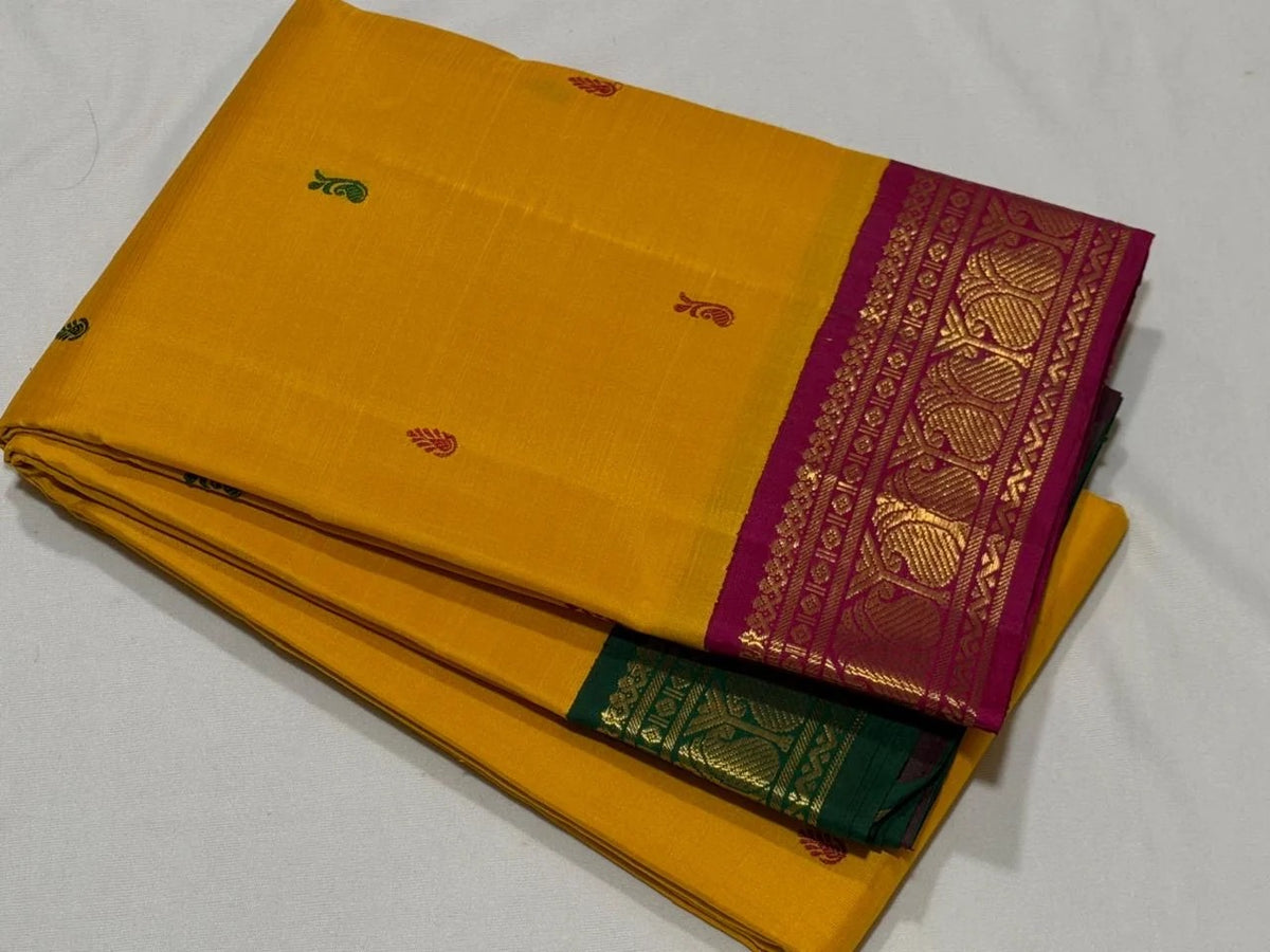Mustard yellow Kanchipuram silk saree with contrasting bottle green and magenta Korvai borders and gold zari bands