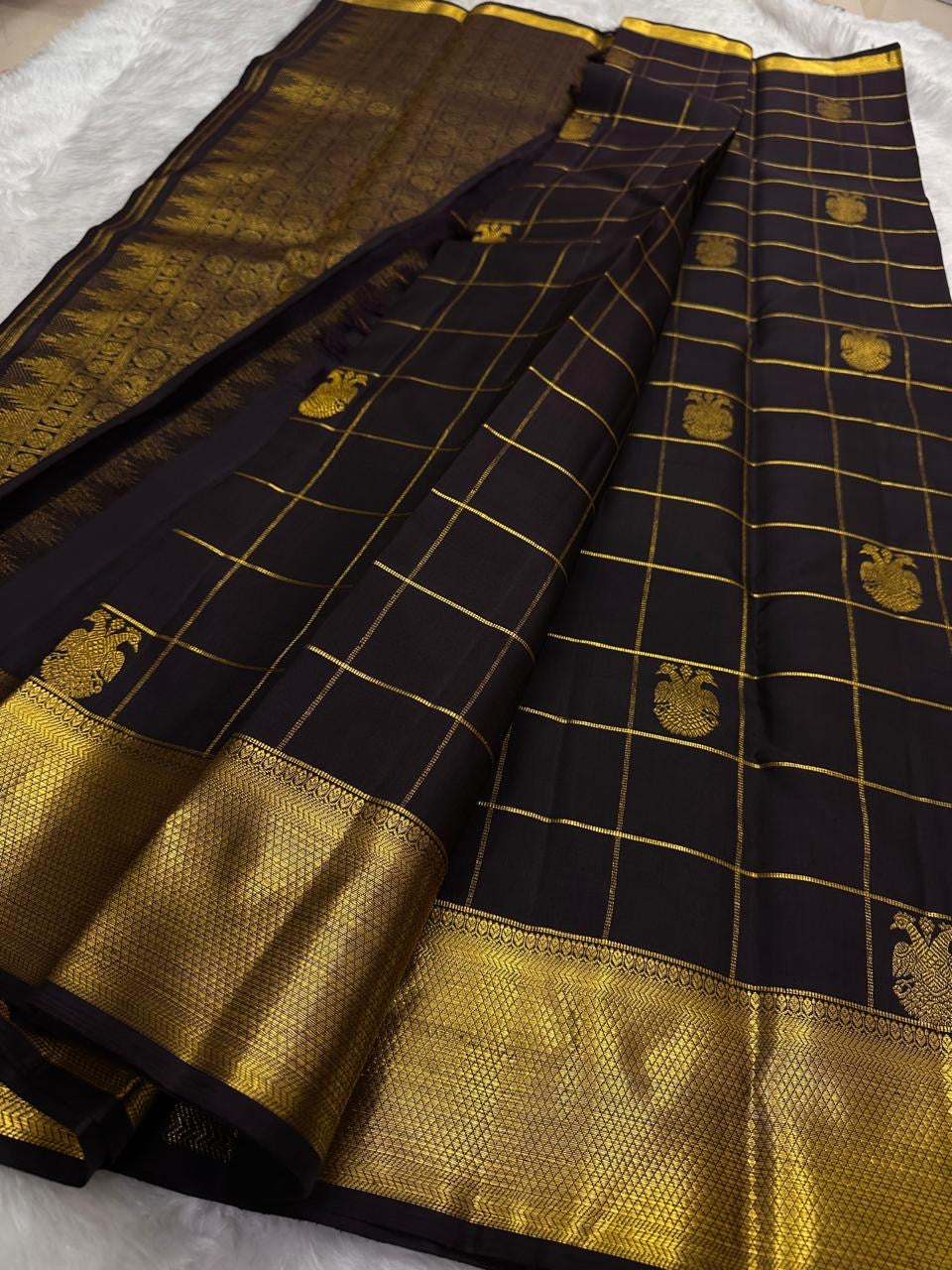 Black kanchipuram silk saree spread with gold zari check pattern and gold border, available in the USA